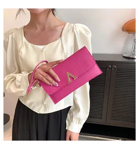 Detail of magenta faux crocodile leather envelope clutch bag with gold V-shaped hardware