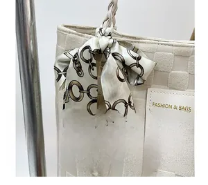 Détail du cabas tissé blanc cassé avec étiquette de mode et foulard en soie à imprimé chaîne