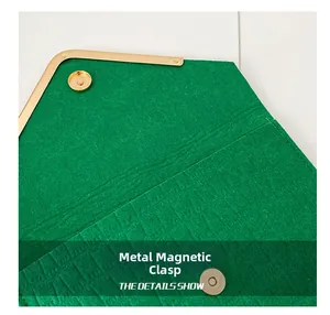 Close-up of green embossed felt envelope bag with golden magnetic snap closure