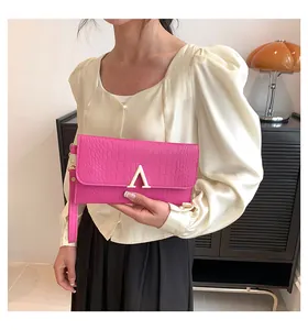 Detail of rose red envelope clutch featuring crocodile pattern and golden V metal buckle