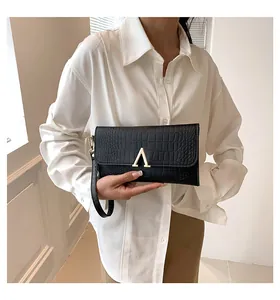 Detail of black faux crocodile leather envelope clutch with gold letter hardware and wristlet
