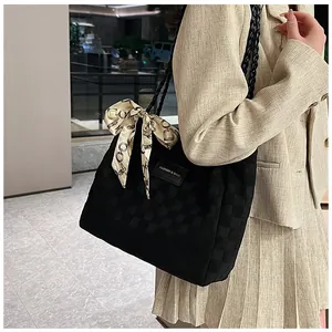 Détail du sac cabas noir à texture damier et foulard en soie sur tenue beige