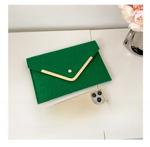 Green crocodile pattern envelope clutch showing size comparison with a smartphone
