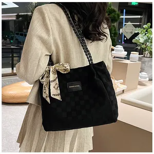 Détail d'un sac cabas tissé noir avec foulard à motif chaîne sur fond minimaliste