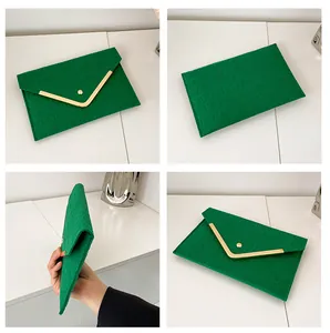 Detailed view of green crocodile texture envelope clutch with V-shape gold trim and snap closure