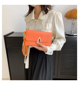 Detail of orange crocodile pattern envelope clutch bag with gold V-shape metal buckle
