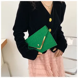Detail of green envelope clutch with checkered texture and V-shaped gold metal trim