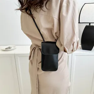 Minimalist black leather crossbody phone bag for women shown with khaki dress