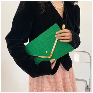 Close-up of vibrant green crocodile-embossed envelope clutch with gold V-shape trim