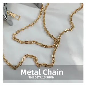 Macro view of detailed gold chain strap and metallic zipper on silver crescent bag