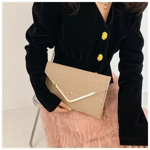 Close-up of beige envelope clutch bag with crocodile texture and gold metal trim