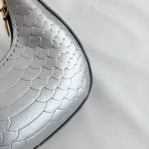 Detailed view of silver crescent bag with scale texture and metallic finish