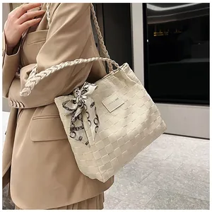 Gros plan d'un sac cabas tissé beige avec foulard en soie décoratif et étiquette mode