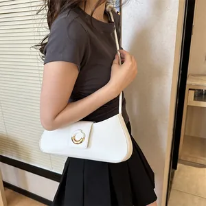 Minimalist white faux leather shoulder bag with a round gold buckle on a model