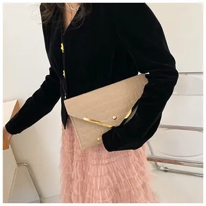 Detail of beige envelope clutch bag with crocodile texture and gold metal trim