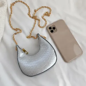 Detail of silver crescent bag with metallic snake texture and gold chain strap