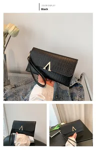 Detail view of black crocodile pattern envelope clutch with golden V-shaped metal clasp