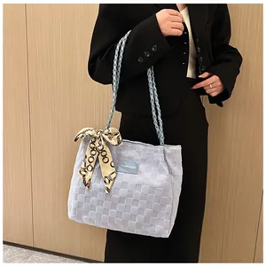 Vue détaillée du cabas tissé bleu clair avec foulard en soie et plaque logo en cuir