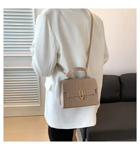Detail of beige faux crocodile leather handbag with elegant gold clasp and handle