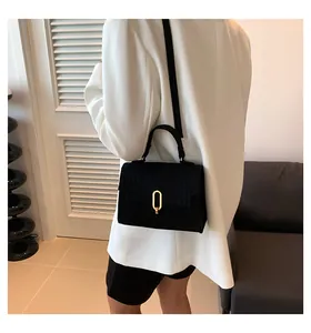 Chic black crocodile embossed crossbody bag with gold buckle shown on a white blazer