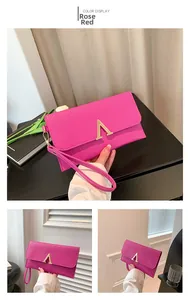 Detail showing fuchsia crocodile pattern envelope clutch with golden V-shaped buckle