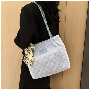 Détail du cabas tissé bleu clair avec écusson en cuir et foulard en soie décoratif