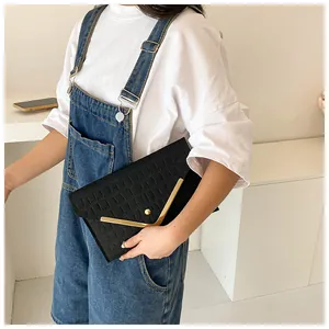 Close-up of black crocodile pattern envelope clutch with golden V-shaped metal trim