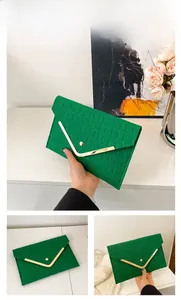 Detail view of green crocodile texture envelope clutch with a golden V-shaped metal buckle