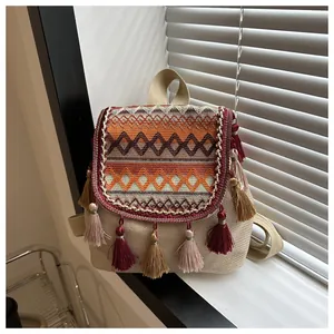 Detail of bohemian canvas backpack featuring woven pattern flap and colorful fringe accents