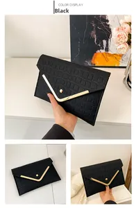 Close-up of black envelope clutch bag with crocodile texture and gold V-shaped trim
