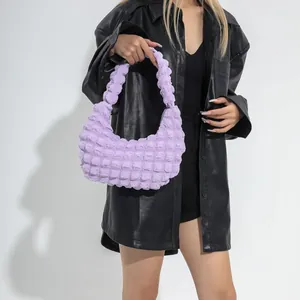 Sac baguette violet clair à texture bulles porté par un mannequin en veste noire