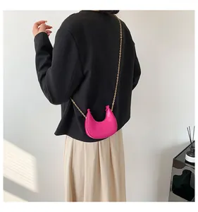 Detail view of hot pink crescent bag with golden chain strap on model outfit
