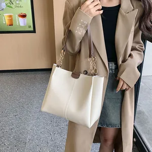 Minimalist beige tote bag with brown chain straps shown on model for daily casual wear