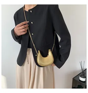 Detail of golden crescent mini bag with crocodile texture and elegant metal chain