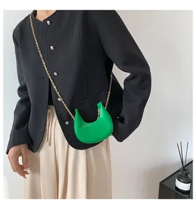 Detail of bright green crescent bag with croc-embossed texture and gold chain strap
