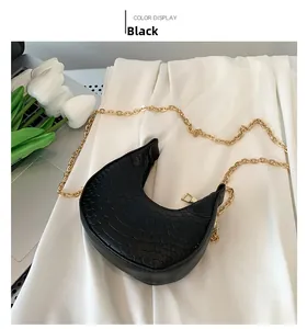 Detail view of black crescent bag with croc-embossed texture and gold chain strap