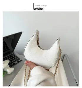Detail view of white crescent bag with embossed texture and golden chain strap