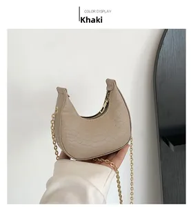 Detailed macro shot of khaki crescent bag featuring scale texture and gold chain strap