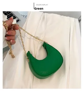 Detail of green crescent bag with crocodile pattern and golden chain strap