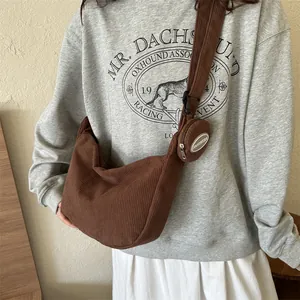 Sac bandoulière demi-lune en velours côtelé marron avec pochette ronde sur modèle