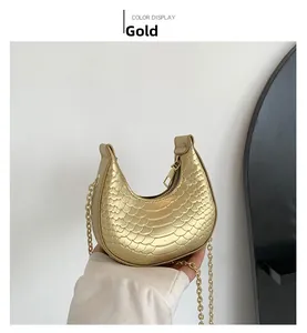 Detail of gold crescent mini bag with snakeskin texture and fine chain strap