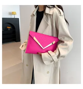 Détail d'une pochette enveloppe rose avec garniture métallique en V et cuir brillant