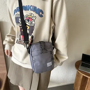 Minimalist grey nylon crossbody bag with Hello Weekend label shown on fashion model