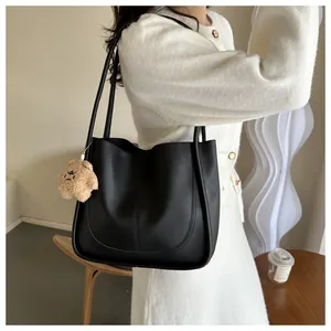 Détail du sac cabas noir avec coutures en U et joli pendentif d'ours en peluche marron