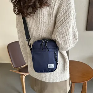 Deep blue nylon crossbody bag with HELLO WEEKEND label shown on model's shoulder