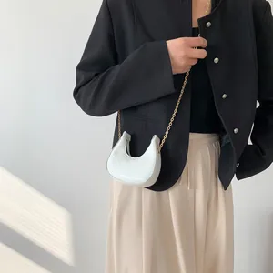 White crescent chain bag with crocodile pattern worn with black blazer and beige skirt