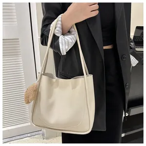 Gros plan d'un sac cabas blanc crème orné d'un joli pendentif ours en peluche marron