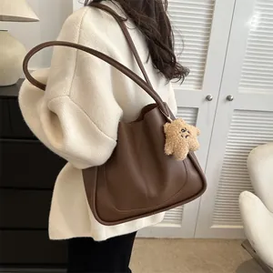Sac fourre-tout en cuir marron avec charme étoile porté élégamment sur l'épaule