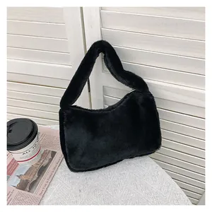 Détail d'un sac à main en peluche noire douce posé sur un bureau avec accessoires cosy