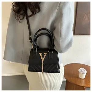 Détail du sac à main en cuir PU noir avec surpiqûres en V et logo à pompon doré
